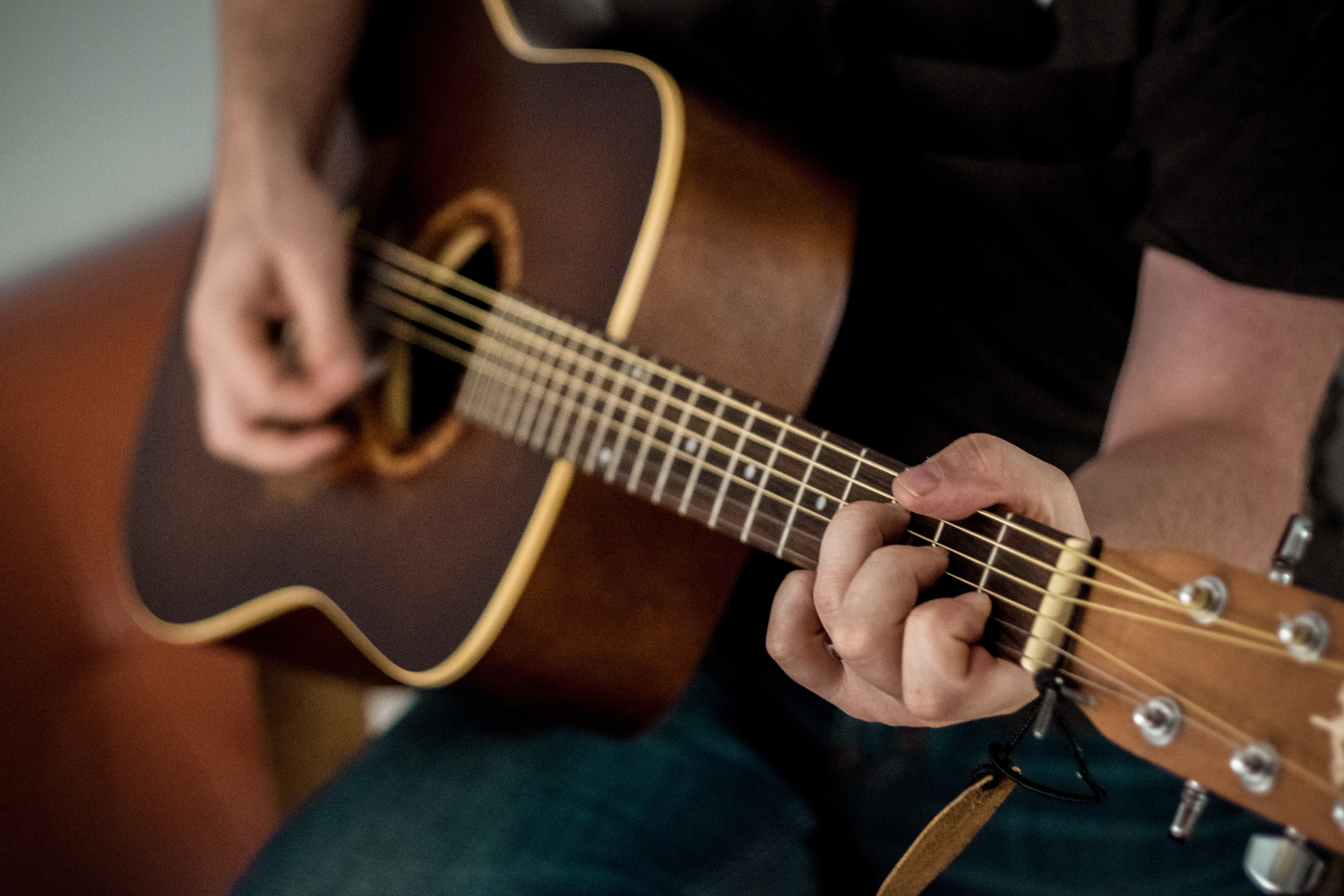 Person playing a brown acoustic guitar