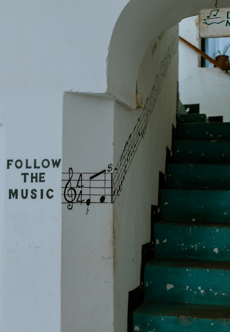 Wall painting reading 'Follow the music' beside staircase